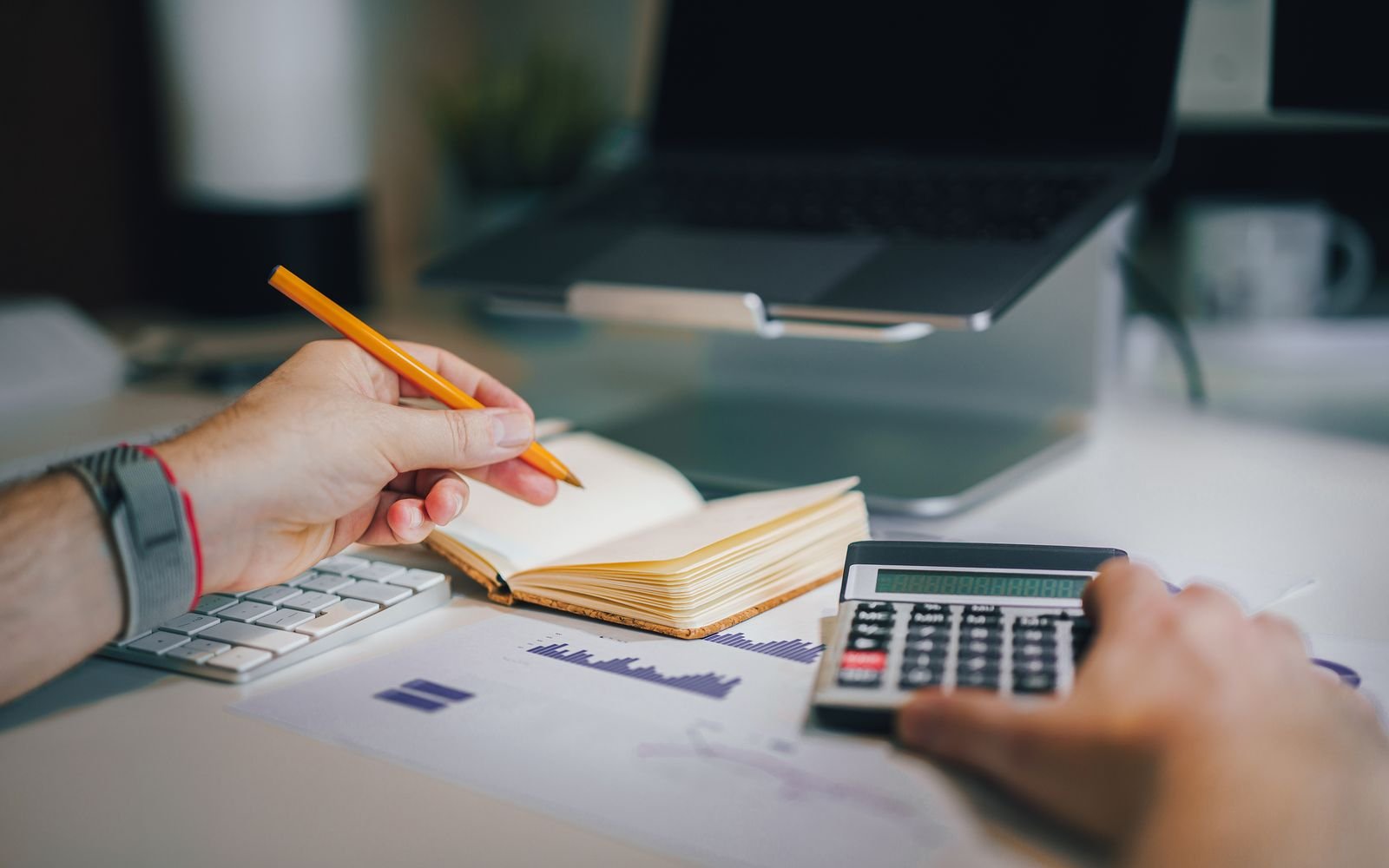 Manos con calculadora y portátil revisando cálculos